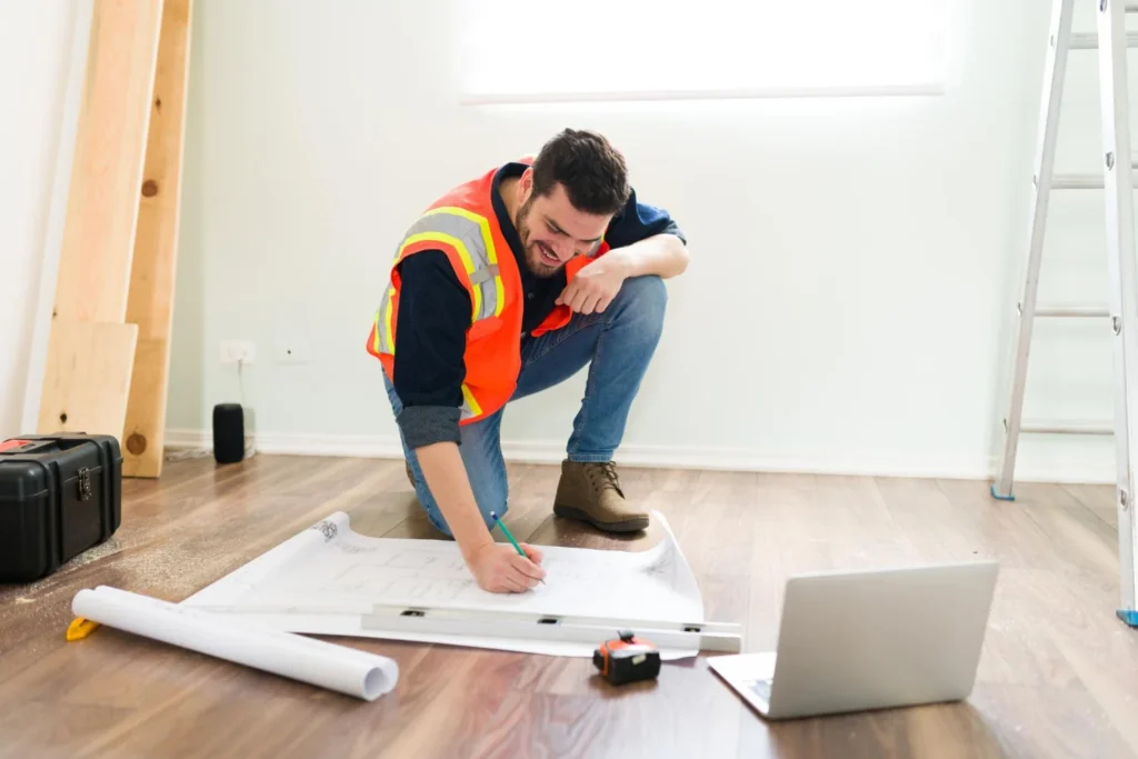 Constructor arrodillado mirando planos
